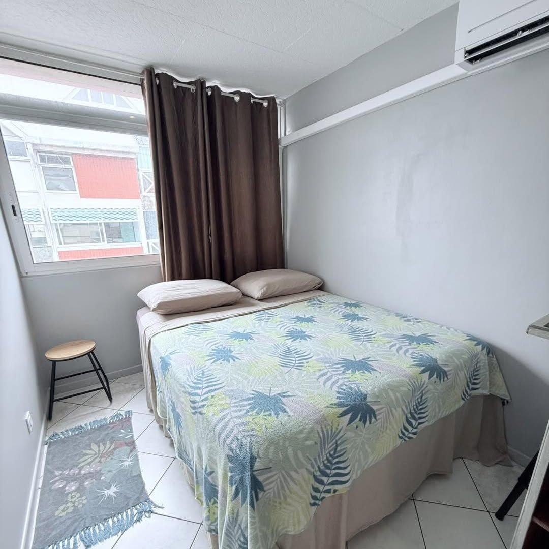 Lit double au parure tropicale sous la fenêtre